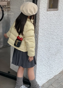 Mädchen mit schwarzer Stepptasche mit roter Schleife und gelber Winterjacke