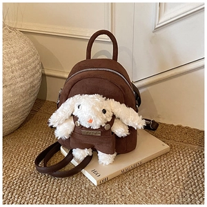 Detail of dark brown mini backpack featuring a plush white bunny with brown overalls