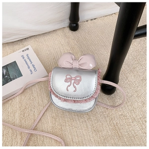 Detail view of silver mini crossbody bag with large pink bow and lace trim decoration
