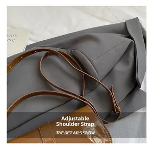 Close-up of adjustable shoulder strap on brown glossy patent leather shoulder bag