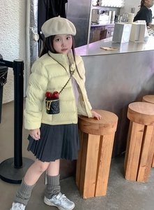 Detailansicht eines Kinder-Outfits mit gelber Daunenjacke und schwarzer gesteppter Tasche