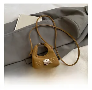 Detail of a brown mini handbag with 3D plush bear and bow tie on leather surface