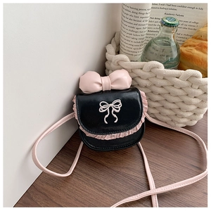 Close-up of a pink bow and lace embroidery on a girls' black crossbody mini bag