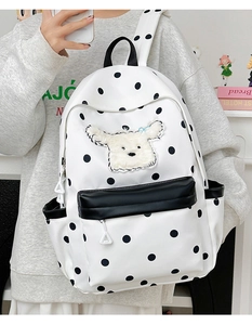 Détail du sac à dos enfant à pois avec écusson chiot en peluche et poche frontale noire