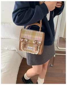 Detail of plaid satchel featuring lace trim, brown leather straps and bow accents