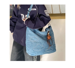 Close-up of blue denim tote bag with white cloud embroidery and star leather tassel charm