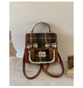 Close-up of vintage plaid school bag featuring lace trim and decorative bows on the flap
