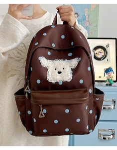 Détail de l'écusson chiot et des pois bleus sur un sac à dos scolaire marron pour enfant