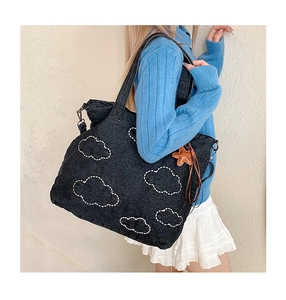 Detail of black denim tote bag with white cloud stitching and star charm accessory