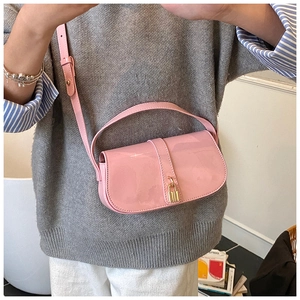 Detail of pink patent leather handbag with golden padlock clasp on a model shoulder