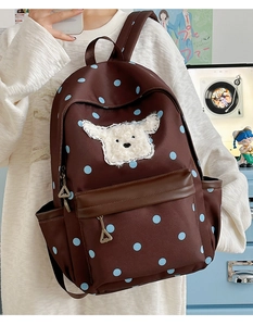 Détail du sac à dos marron à pois avec applique de chien en peluche et fermeture métallique