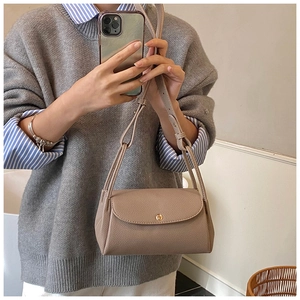 Close-up of khaki litchi grain leather flap bag with gold round snap button and strap