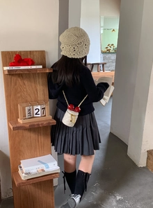 Mini-Zylindertasche mit roter Schleife und Goldkette auf dem Rücken des Models