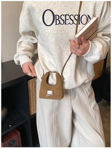Close-up of brown suede mini bear bag with bow detail on model in casual cream outfit