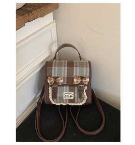 Detail view of plaid backpack with lace trim, bows and vintage leather straps