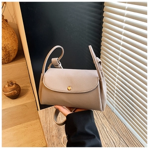 Detail of greige lychee grain leather crossbody bag with a round golden magnetic buckle clasp