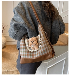 Detail of checkered shoulder bag featuring a plush bear and lace pocket design