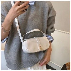 Detail shot of the glossy cream shoulder bag featuring a gold clasp and smooth patent finish