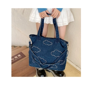 Detailed view of cloud patterns and quilting on the dark blue denim tote shopping bag