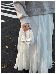 Detailed view of mini white bow handbag with silver zipper shown in autumn street scene