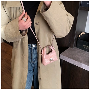 Pink mini crossbody bag featuring panda pendant and bowknot, shown on a beige coat model