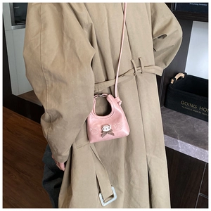 Detail of pink mini bear bag with plush bear charm and plaid bow on beige coat