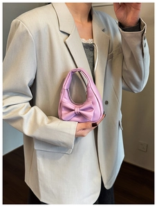 Mini pink bow handbag shown held by hand to display its small size and cute style