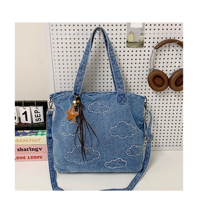 Detail of blue denim tote bag featuring white cloud embroidery and star tassel pendant