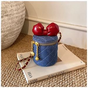 Detail einer gesteppten Denim-Mini-Beuteltasche mit roter Schleife und goldener Kette