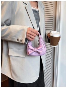 Detailed view of a mini pink girl's handbag featuring a large decorative bow and leather texture