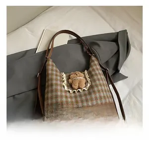 Detailed view of vintage plaid pattern and cute plush bear charm on the shoulder bag