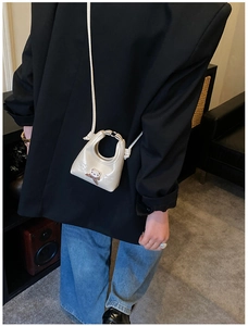 Mini cream bear crossbody bag with cute bow charm shown on a chic black blazer