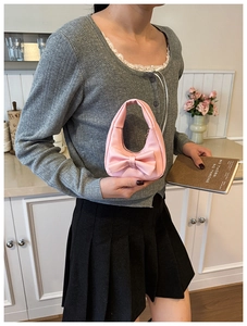 Pink bow handbag for girls shown with gray cardigan and black pleated skirt