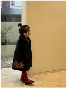 Detail of child wearing a black faux fur coat with a stylish leopard print handbag