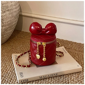 Detail einer roten gesteppten Mini-Beuteltasche mit Schleife und goldener Herzkette
