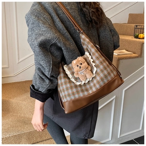 Detail view of plaid kids crossbody bag with plush bear and stylish ruffled pocket