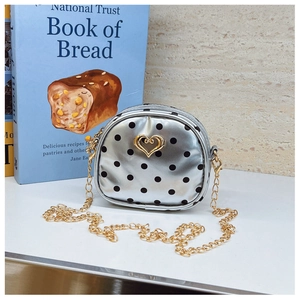 Detailansicht der silbernen gepunkteten Mini-Rundtasche mit goldenem Herzverschluss