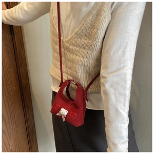 Side view of a red mini plush bear crossbody bag worn by a child in an indoor setting