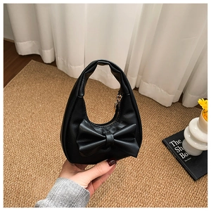 Close-up of black PU leather girls' mini handbag with a large bow and top handle detail