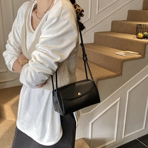 Minimalist black pebble leather crossbody bag with gold round buckle for daily commute
