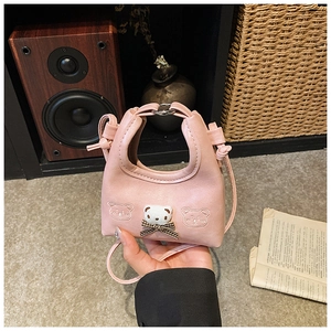 Detailed macro view of the pink girl's handbag featuring a plush bear with a plaid bow