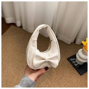Close-up of white mini bow handbag with gold zipper and artificial leather texture