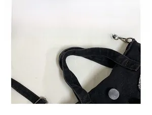 Dettaglio dei manici della borsa in denim con tracolla e ciondolo a sfera di peluche