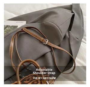 Detail of adjustable brown leather shoulder strap with metal buckle on leopard handbag