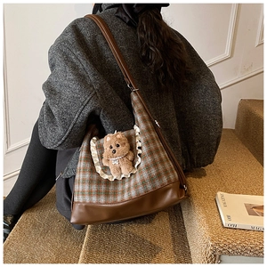 Kid's plaid crossbody bag with teddy bear charm shown on model in wool coat