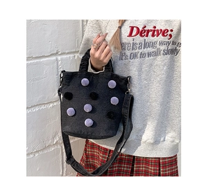 Close-up of black denim tote bag with purple plush polka dots on a casual model