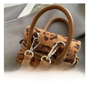 Macro detail of the silver metal hook and leopard print texture on a mini handbag