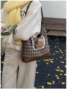 Detail of checkered crossbody bag with plush bear charm and faux leather base