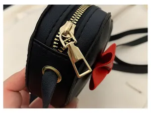 Close-up of the smooth golden metal zipper on this black heart-shaped girls shoulder bag