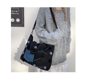 Dettaglio borsa tote in denim con design patchwork vintage e pompon decorativi